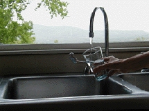 Description: a cup under a water faucet